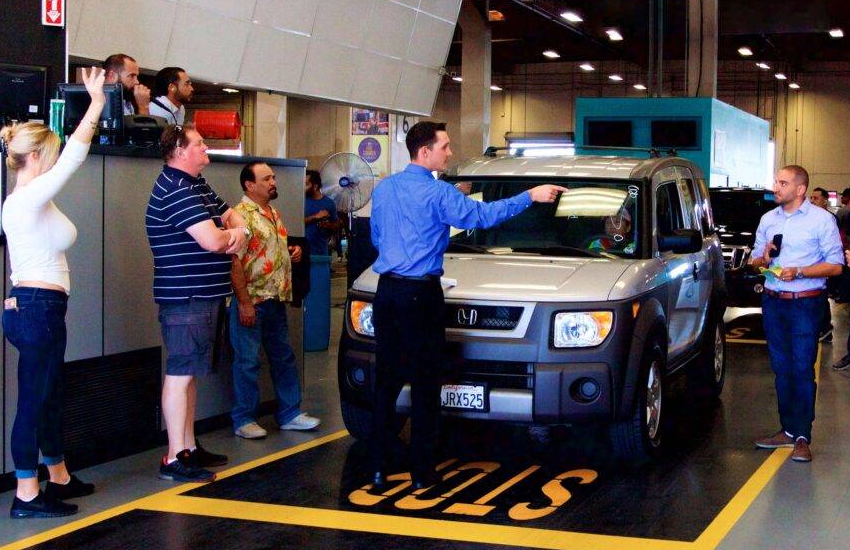 Vehicle inspection at an auto auction — staff presenting a vehicle to buyers at the auction block